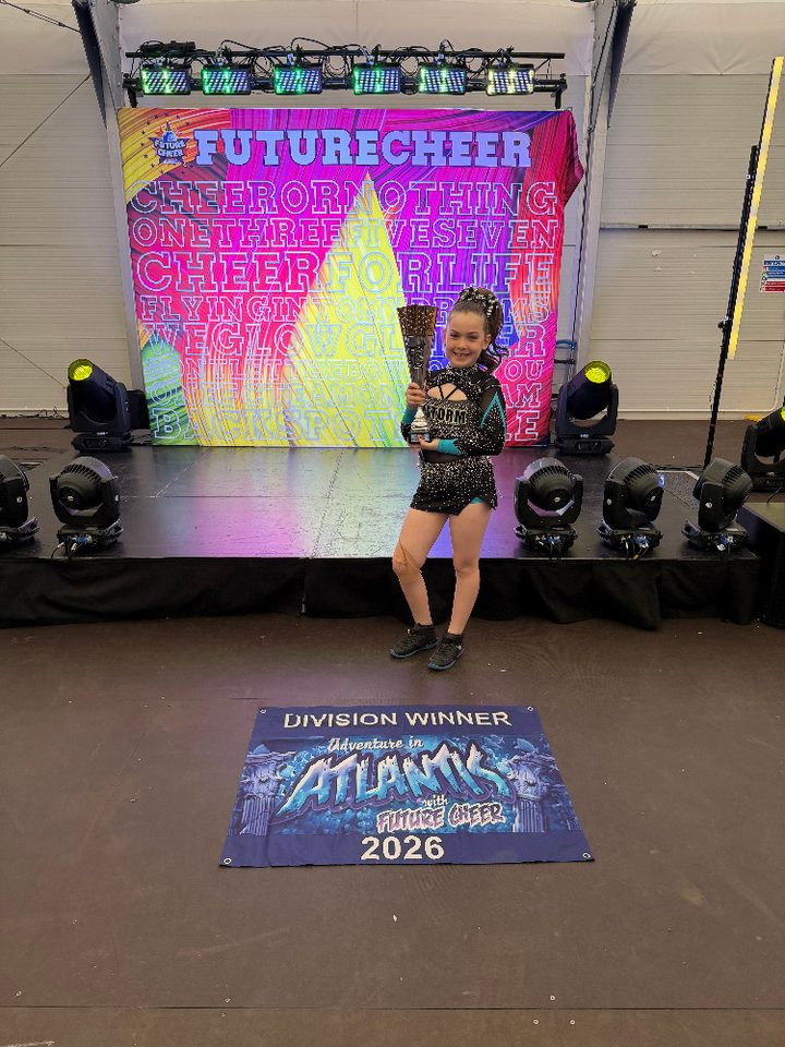 Grace holding a trophy in her Storm Athletics uniform at a Future Cheer competition